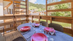 Una terraza de madera con una mesa lista para comer, con vistas a un paisaje montañoso.