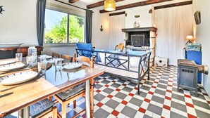 A dining area with a checkered floor, wooden furniture, and a fireplace. - La Sablière by Interhome (Ile d'Oléron)