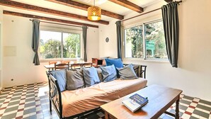 A cozy room with a checkered floor, a sofa with cushions, a wooden table, and a hanging light fixture. - La Sablière by Interhome (Ile d'Oléron)