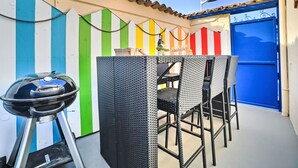 An outdoor patio with a grill, wicker furniture, and a blue door. - Cheray 1 by Interhome (Ile d'Oléron)