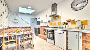 A modern kitchen with a dining area, featuring a skylight, a large clock, and a brick backsplash. - Cheray 1 by Interhome (Ile d'Oléron)