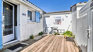 Una terraza de madera con una bicicleta y un cartel en una pared blanca.