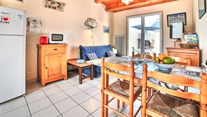 Una cocina acogedora con vigas de madera, una mesa de comedor con sillas, un refrigerador, un microondas y un televisor.
