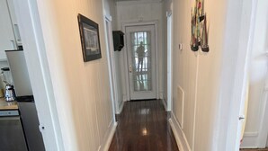 A hallway with wooden flooring, white walls, and a door at the end. - Charming, 1-bedroom in downtown Wilmington! (Wilmington)