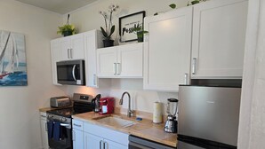 A modern kitchen with white cabinets, a stainless steel refrigerator, a coffee maker, and a blender. - Charming, 1-bedroom in downtown Wilmington! (Wilmington)