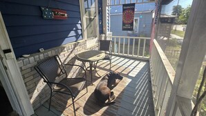 A covered porch with a brick wall, a welcome sign, a table and chairs, and a dog. - Charming, 1-bedroom in downtown Wilmington! (Wilmington)