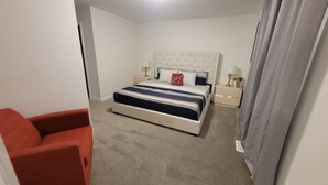 A bedroom with a bed, nightstands, a chair, and a curtain.
