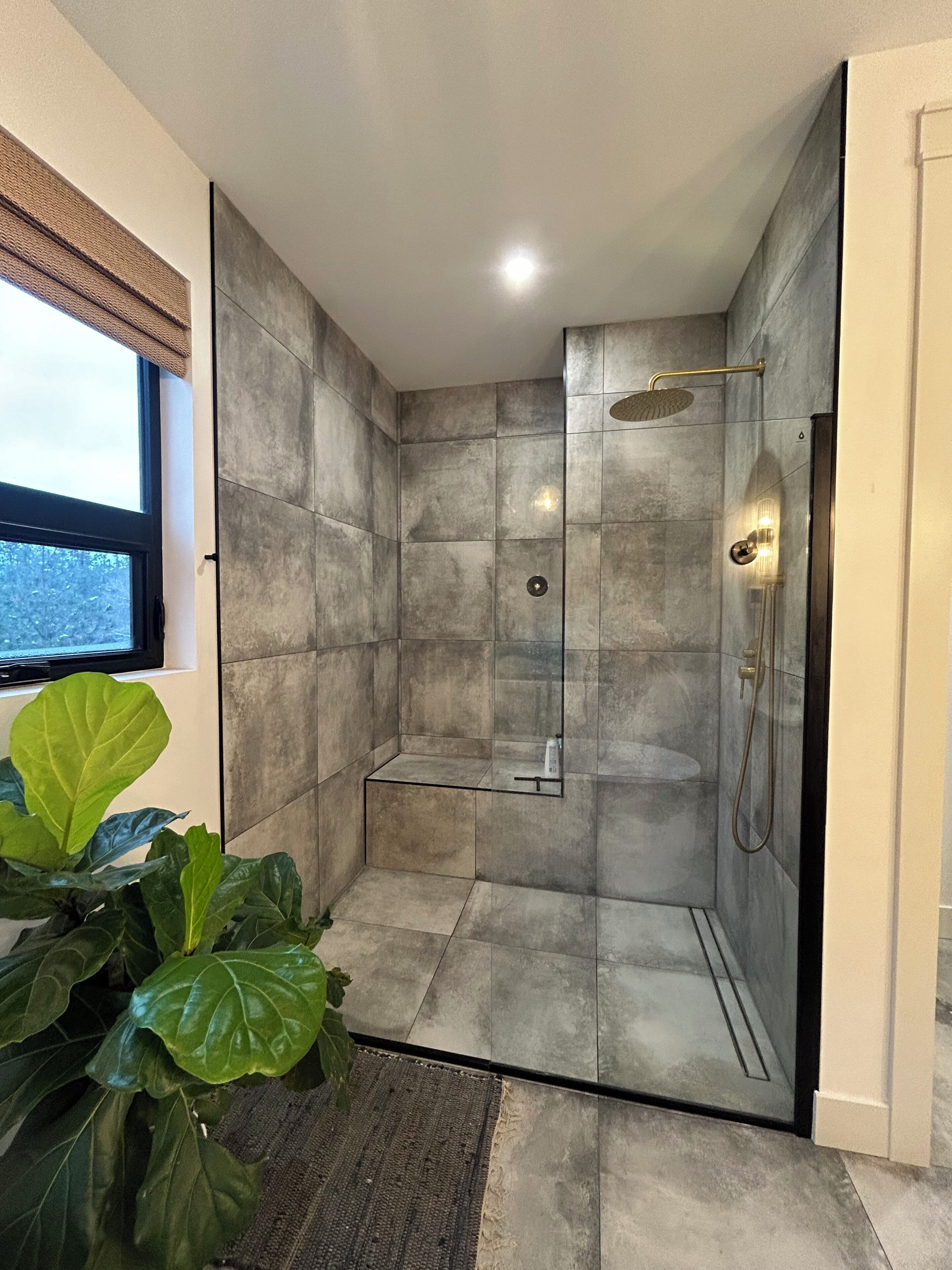 A modern shower with a glass door, a handheld showerhead, and a wall-mounted faucet.