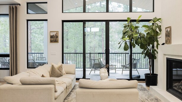 A spacious living room with a large window, a fireplace, and a balcony with outdoor seating.