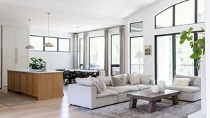 A spacious living area with a large sofa, a wooden coffee table, and a kitchen island with a plant.