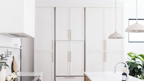 A modern kitchen with white cabinetry, a wooden island, and pendant lighting.