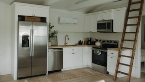 Une cuisine moderne avec des meubles blancs, des appareils en acier inoxydable et une échelle en bois.