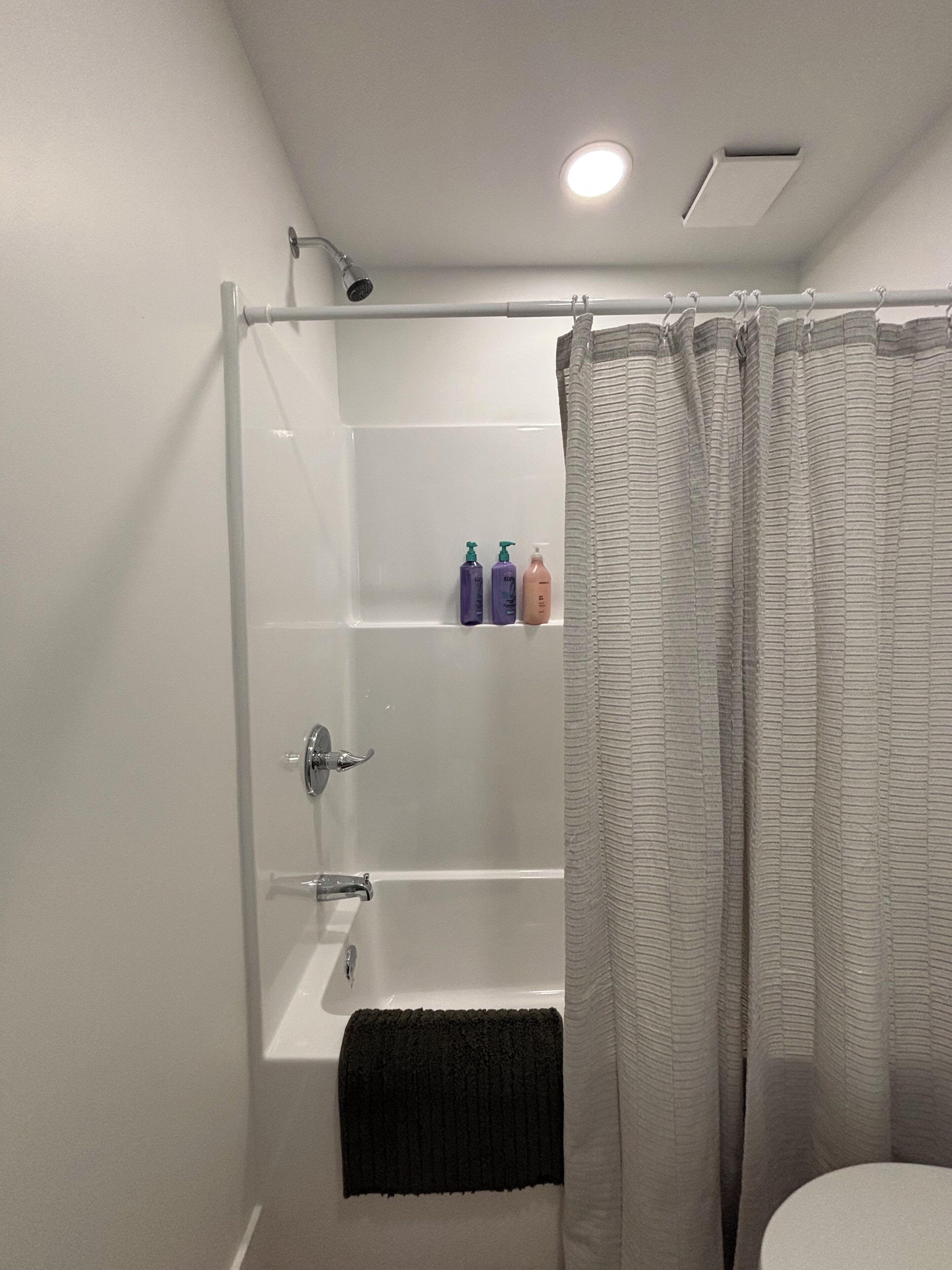 Een moderne badkamer met een douchecabine van glas, een badkuip en een toilet.