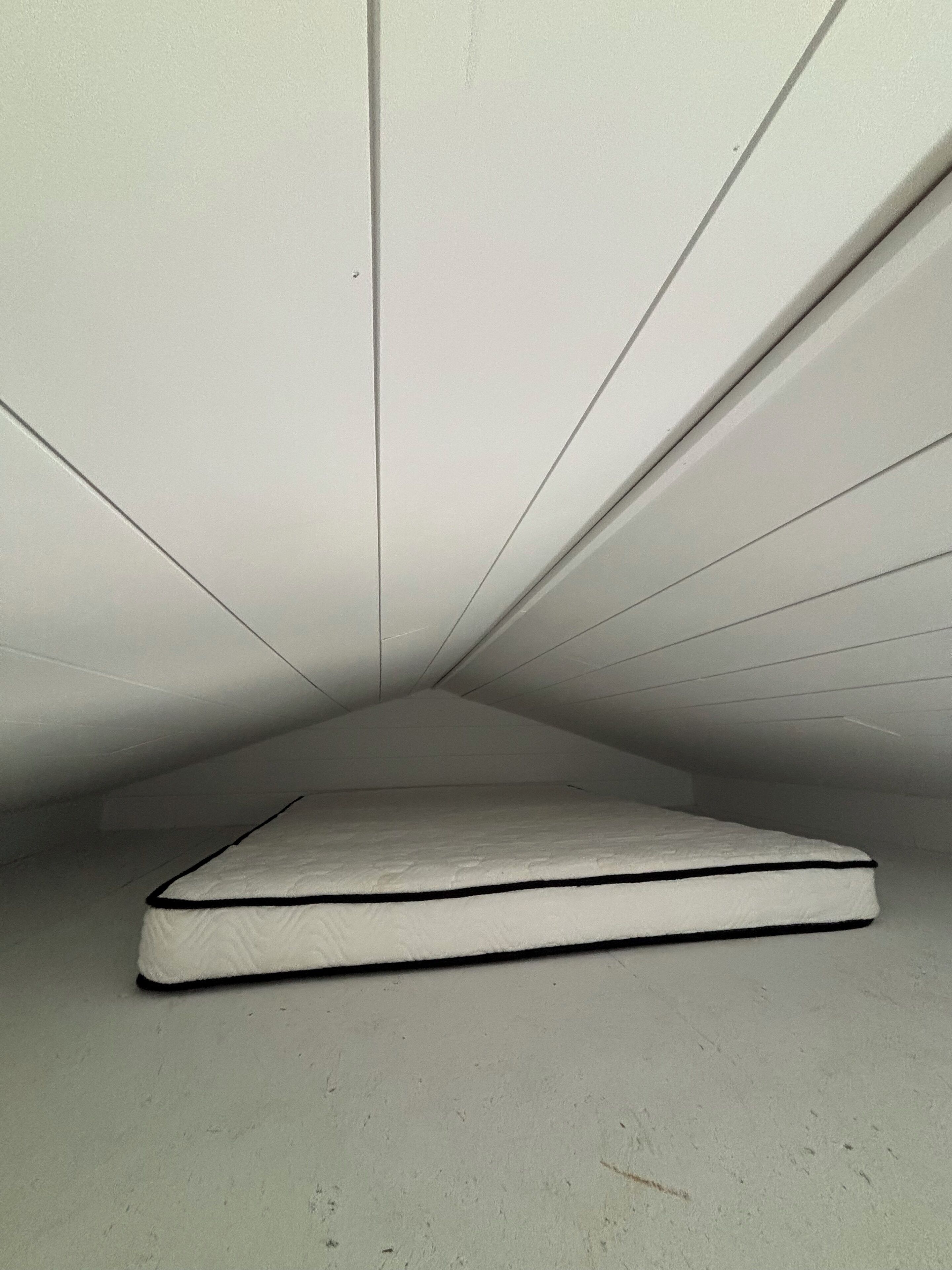 Una habitación con un colchón en el suelo, sin muebles ni comodidades visibles.