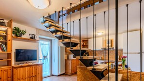 A modern kitchen with wooden cabinetry, a built-in oven, and a dining area with a wooden table and chairs. - Ca' Il Nido by Interhome (Domaso)