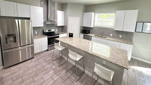 Een moderne keuken met roestvrijstalen apparatuur, granieten aanrechtbladen en witte kastjes.