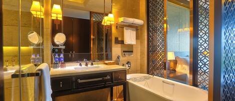 A modern bathroom with a large mirror, two sinks, a bathtub, and a glass shower enclosure.