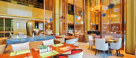 A modern hotel lobby with a marble reception desk, comfortable seating areas, and a visible staircase.
