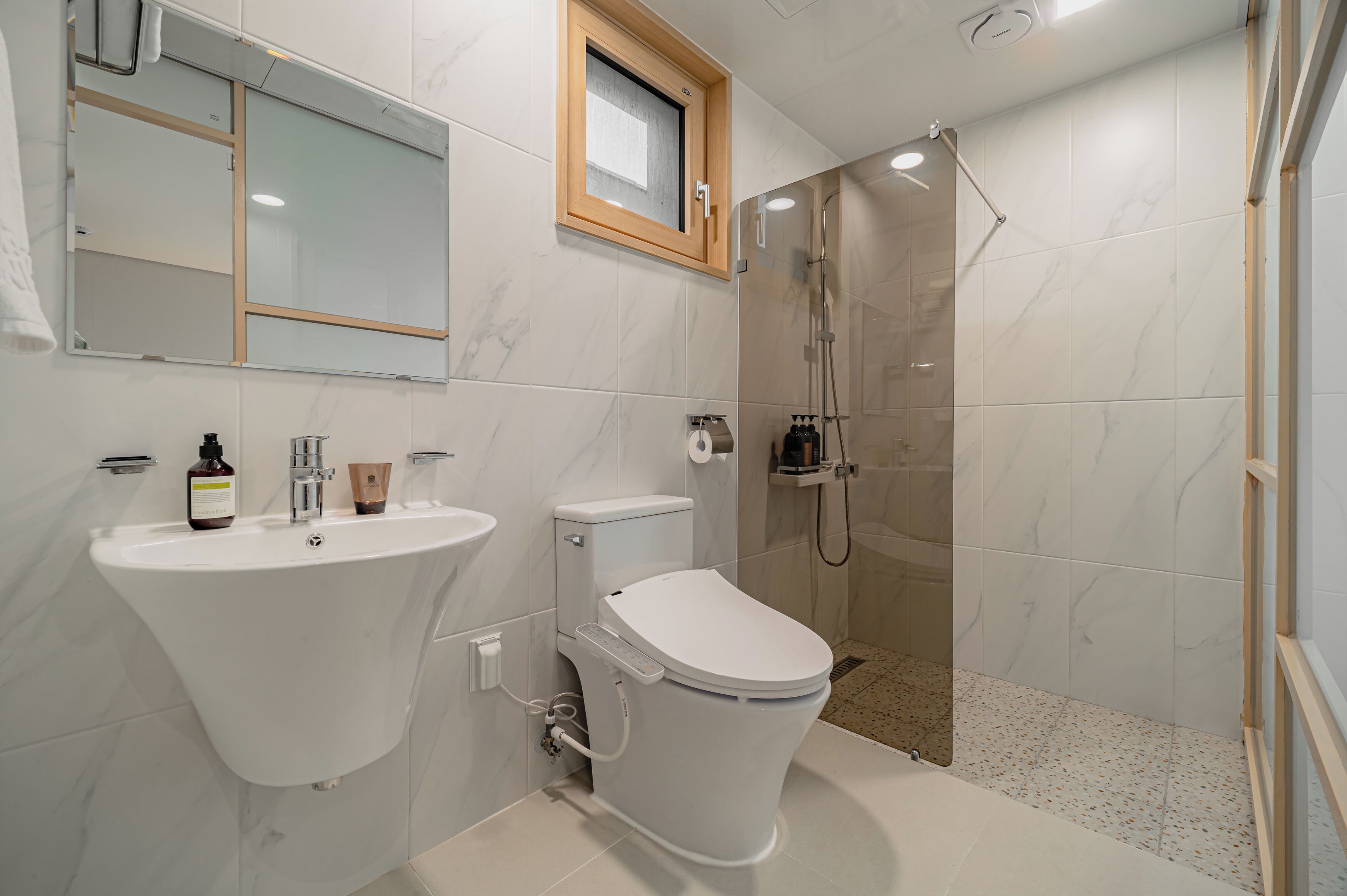 A modern bathroom with a white sink, toilet, and shower.