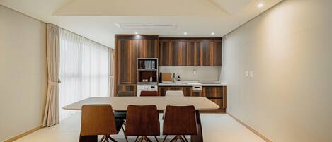 Una cocina moderna con armarios de madera, una mesa de comedor con sillas y un amplio ventanal con cortinas.