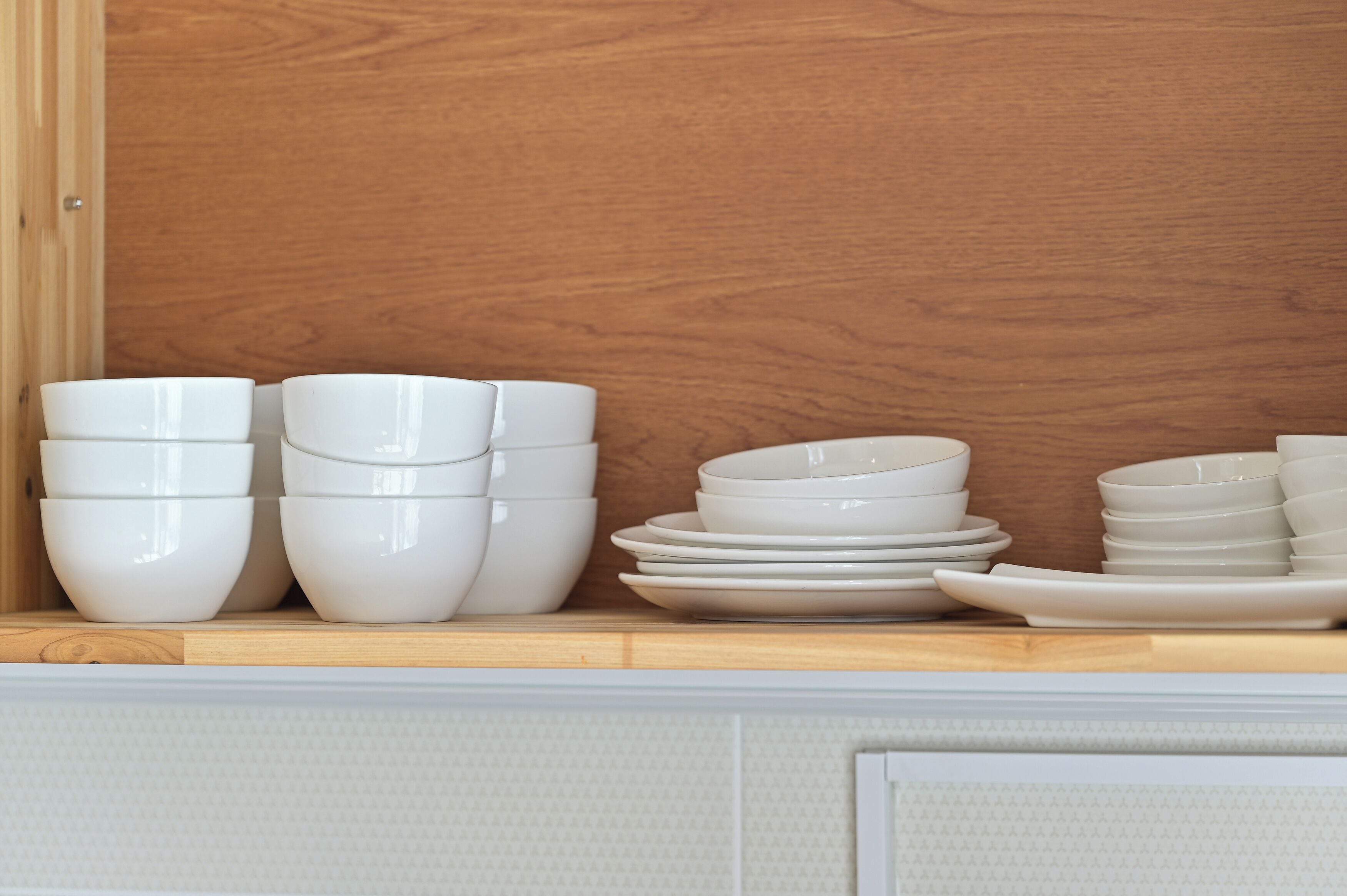 A kitchen counter with white bowls and plates stacked on it.