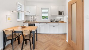 A modern kitchen with white cabinets, a wooden dining table, and a herringbone floor pattern. - V kapradí by Interhome (Hřensko)