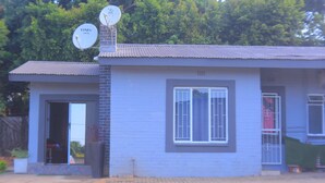 Un pequeño edificio de una sola planta con techo plano y una antena parabólica en el techo.