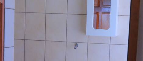 A bathroom with a white pedestal sink, a mirror cabinet, and a tiled floor.