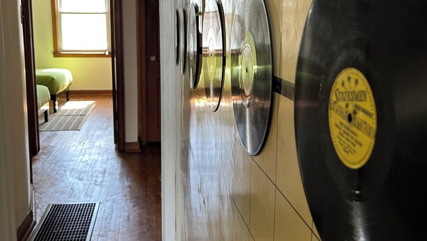 Un pasillo con una colección de discos de vinilo en la pared y un suelo estampado.