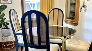 Un comedor con una mesa redonda de vidrio, rodeada de sillas con respaldo de malla y asientos acolchados.
