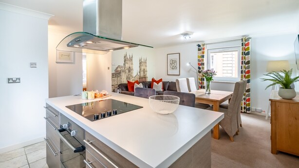 A modern kitchen with a central island, stainless steel appliances, and a glass-fronted range hood.