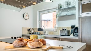 A modern kitchen with a central island, a window with a view of a brick building, and various kitchen appliances.