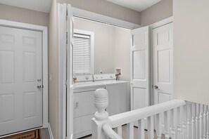 Laundry room with a washing machine and dryer, featuring a window with blinds.
