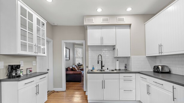 A modern kitchen with white cabinets, a wooden floor, and a built-in stove. - 3br 2ba hse  AC WiFi 3 blks to Xcel Event Center, dining,&bars 6.8 mls to airprt (Saint Paul)