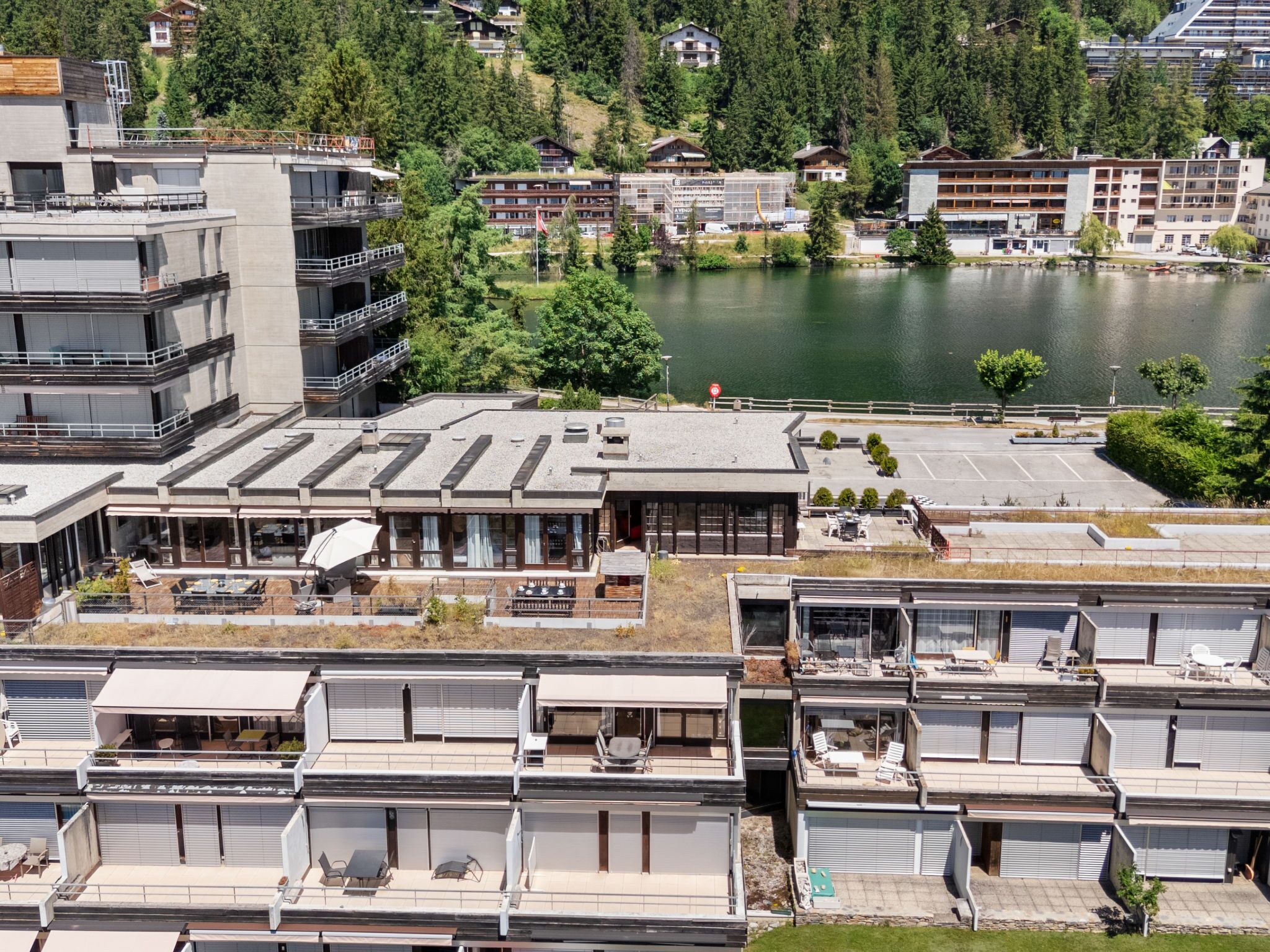 Um hotel moderno com vários andares, áreas de estar ao ar livre e vista para um lago.