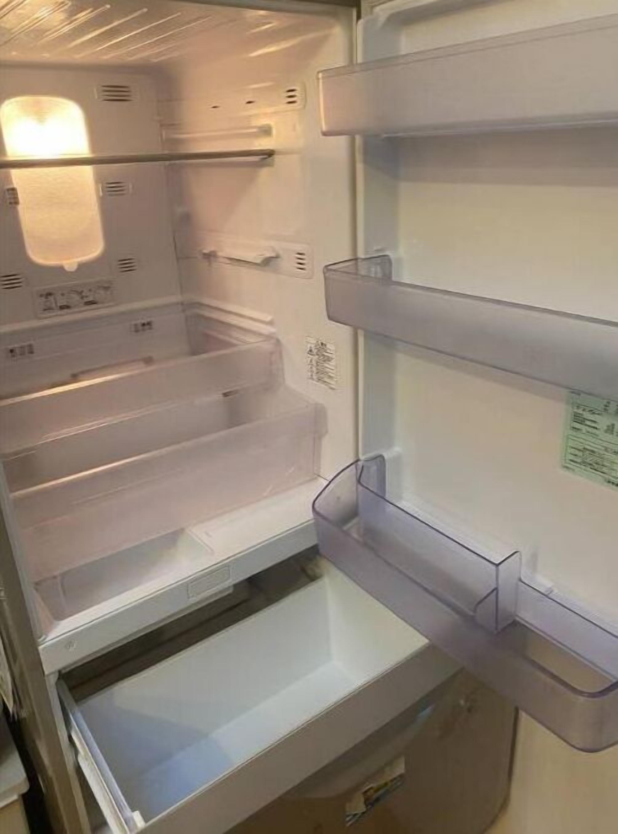 Een open koelkast met transparante plastic planken en een vriesvak.