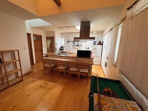 Cocina compacta con comedor, muebles de madera y mesa de billar.