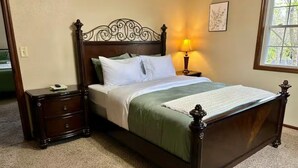 A neatly made bed with a wooden headboard, a bedside table with drawers, and a lamp on the nightstand.