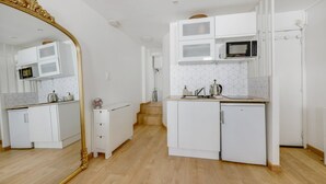 A compact kitchen with white cabinetry, a microwave, and a sink. There is a wooden staircase leading to another room.