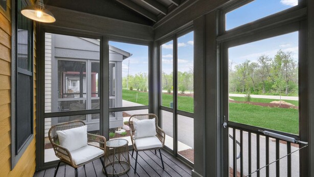 A covered porch with wicker chairs and a table, large windows offering a view of a house and greenery. - Fun In The Sun â€“ A Bright andBreezy Getaway in Navvy Town (Ottawa)
