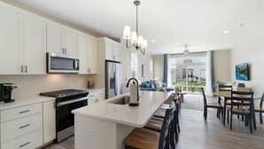 A modern kitchen with white cabinets, a central island, a built-in oven, and a microwave. - Fun In The Sun â€“ A Bright andBreezy Getaway in Navvy Town (Ottawa)