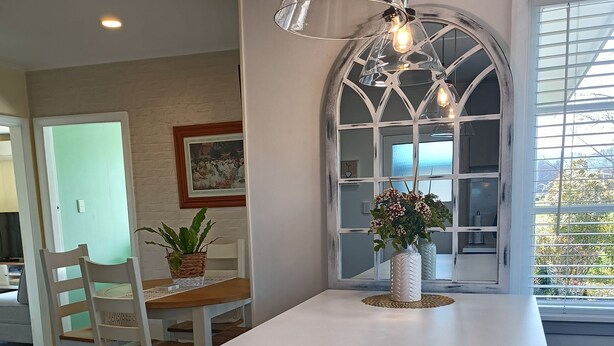 A kitchen with a white countertop, a hanging light fixture, and a window with a view of greenery. -  Country Cottage Delight in the Hurunui.
(Spotswood/Cheviot)
 (Spotswood)