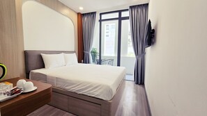 Una habitación de hotel con cama, mesita de noche y televisor instalado en la pared.