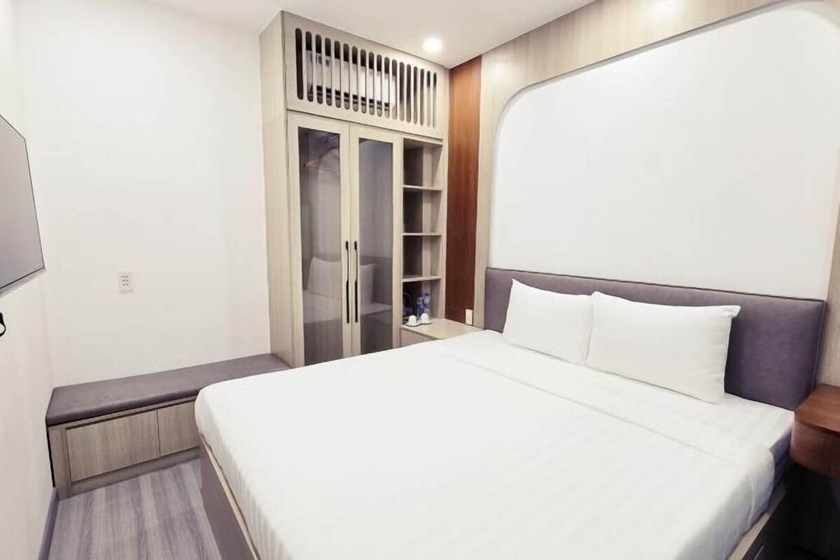 A bedroom with a bed, a wardrobe, and a bedside table.