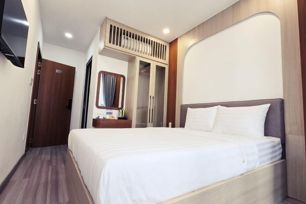 A hotel room with a large bed, a wardrobe, a mirror, and a TV mounted on the wall.