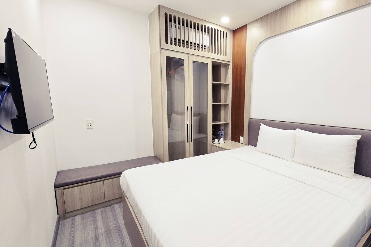 Une chambre d’hôtel équipée d’un lit, d’un téléviseur fixé au mur, d’une armoire et d’une table de chevet.