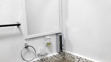 A bathroom with a glass sink, a towel rack, a toilet paper holder, and a mirror.