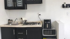 Una cucina compatta con pensili neri, un fornello a gas, una macchina da caffè e un forno a microonde.