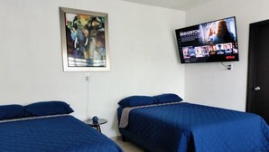 Una camera d'albergo con due letti, una televisione montata a parete e un quadro appeso al muro.