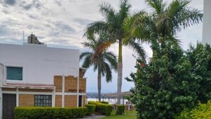 Un cortile con area pavimentata, palme e un edificio dalla facciata bianca con dettagli in mattoni.
